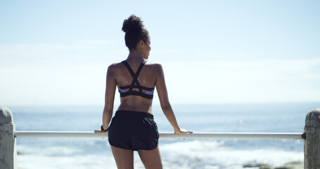 Woman, exercise and thinking on break at beach promenade, space and sky for fitness. African...