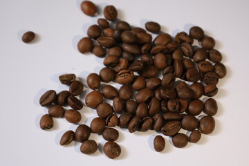 Roasted brown coffee beans, isolated on a white background, form a heap, ready for a rich, dark espresso drink