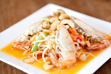 Som tam Thai with river prawns and roasted cashew nuts served on a white plate, presenting authentic street food and vibrant flavors.