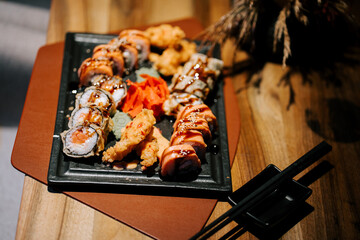 Sushi platter with various rolls and shrimp served on a black tray at a restaurant