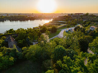 Sunset view over Petrovaradin Fortress in Novi Sad with lush greenery and river reflections during a peaceful evening