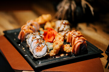 Sushi platter featuring assorted rolls and fried shrimp in a cozy dining setting