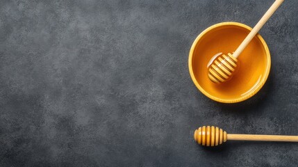 Honey in bowl with dippers on dark stone background