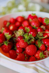 Fresh sweet strawberries in a white bowl on a white background. Seasonal berries.
