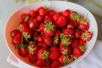 Fresh sweet strawberries in a white bowl on a white background. Seasonal berries.