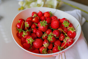 Fresh sweet strawberries in a white bowl on a white background. Seasonal berries.