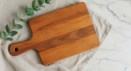 Overhead shot of a rustic wooden cutting board, ideal for charcuterie or pizza presentations, surrounded by greenery.

