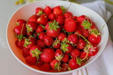 Fresh sweet strawberries in a white bowl on a white background. Seasonal berries.