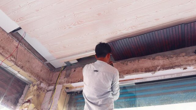 Worker Installing Ceiling Panel in Renovated Shop
