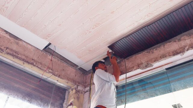 Handyman uses drill tool for sheet attachment above