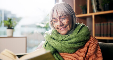 Senior woman, smile and reading book on sofa with story, poetry or novel in living room at house....