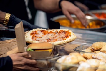Street vendor handing over fast food - pseudo-pizza and burger to a customer. Casual urban eating concept