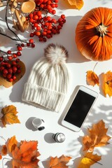 Autumn flat lay with hat smartphone pumpkin leaves and berries