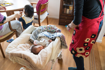 自宅のベビーチェアで寝る日本人の乳幼児と家族