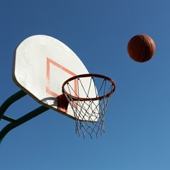 Basketball Hoop and Ball Frozen in Mid-Air against Clear Blue Sky