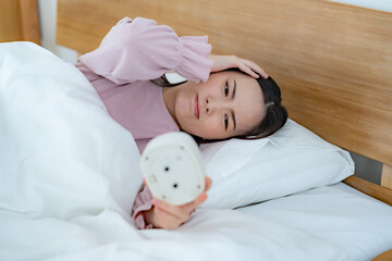 目覚まし時計を見る女性