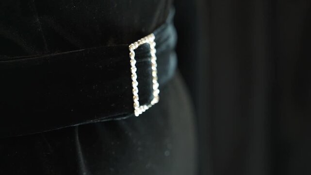 A belt with shiny rhinestones on a black women's dress. Diamonds decorate the belt for women's suits and dresses.