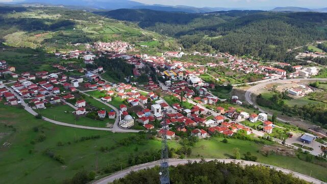 Breathtaking 4K drone footage of Keles town center in Bursa, Turkey. Aerial view of red-roofed houses, mosque, roads, lush greenery, and surrounding forested hills in springtime tranquility. ultrahd