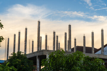 construction site of a multi-storey building in progress, showing scaffolding, brick walls, concrete columns structural in house construction sites blue sky air with golden clouds sunset background