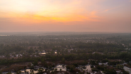 A breathtaking view of a savanna landscape at sunrise, with warm hues of orange and pink illuminating the sky. A solitary tree stands prominently amidst the wilderness at Koh Phra Thong, Phang Nga.