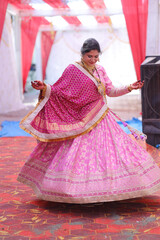 Naklejka premium Indian Woman in Traditional Pink Lehenga and Dupatta at Wedding Venue