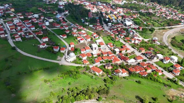 Stunning 4K aerial footage of Keles town center in Bursa, Turkey. Features red-roofed homes, a mosque with a dome, winding roads, green hills, and peaceful rural architecture. Turkiye ultrahd video