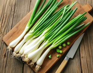 Freshly harvested green onions are neatly arranged on a wooden cutting board. A sharp knife rests beside them, while some chopped onion pieces add to the preparation for cooking.
