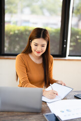  Freelancer Woman writing on notebook  Sitting At Home office . Happy Smiling Working Online While...