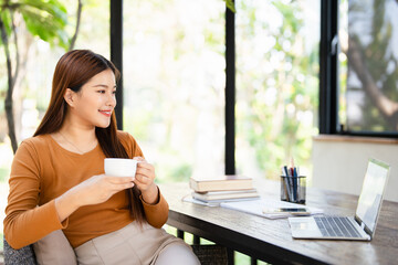 Young smiling businesswoman on coffee break in home office.