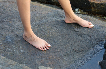 A woman's feet are bare on a rock