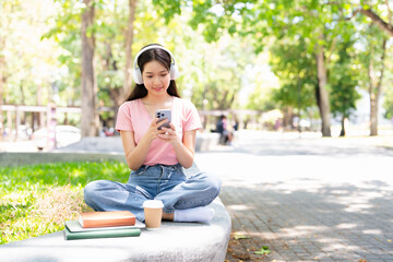Student Woman sitting outdoor texting on a mobile phone or Listening Music Media Entertainment ...