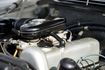 The engine and battery compartment of a classic car, with its detailed mechanical and electrical components, the vintage engineering powering the vehicle.