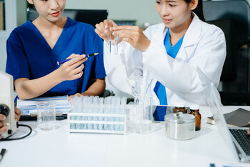 Healthcare professionals use a tablet and test tube to document research and innovation in a...