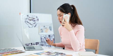 Interior designer talking on cellphone with client, discussing new project, In studio office with blueprint drawing color swatches and material, design develop, Copy Space