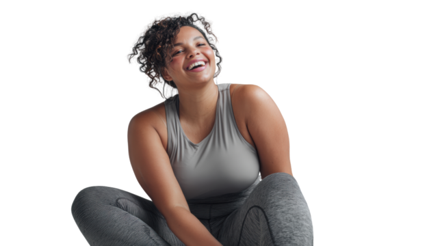 Cheerful woman in activewear smiling while sitting on the floor, promoting fitness and positivity.