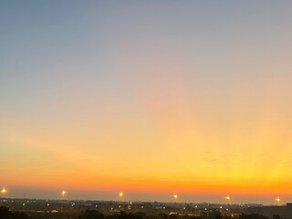 A vibrant golden sunset over a cityscape, with glowing streetlights and a soft gradient sky transitioning from orange to blue.
