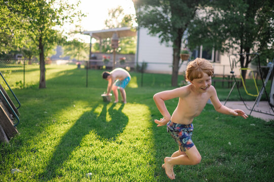 Children playing with water balloons on sunny backyard day
