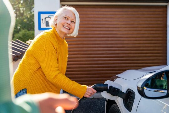 Woman charging electric car at home in a sustainable setting