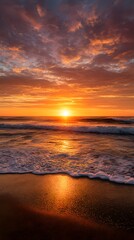 Obraz premium Golden sunset illuminates the serene beach and vast sea, painting the sky with vibrant clouds and reflecting on gentle waves