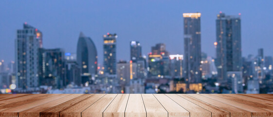 Tranquil dark city modern cityscape sunset bokeh lights orange glow urban landscape evening view. Wood tabletop floor night metropolis glow building