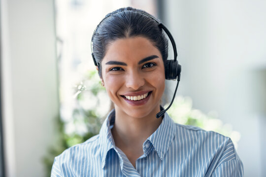 Smiling customer service representative using a headset in an office