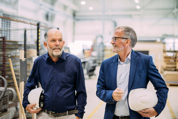 Two engineers discussing plans in a factory setting