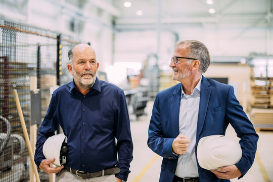 Two engineers discussing plans in a factory setting