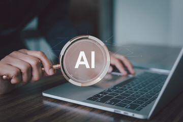 A magnifying glass hold by a person over a laptop screen emphasizes "AI," suggesting the exploration, discovery, or deep dive into artificial intelligence concepts. Research, and future trends.