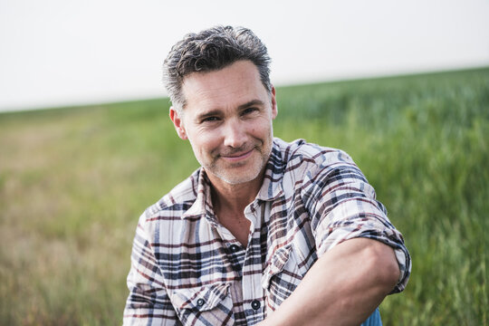 Smiling mature man sitting on field