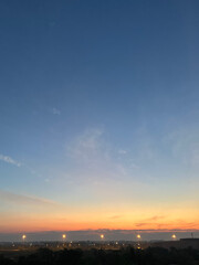 A tranquil cityscape at twilight, featuring a soft blue sky transitioning into warm sunset hues.