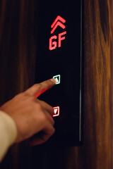 Close-up of a finger pressing an elevator button, displaying floor number 04 on a dark wood panel....