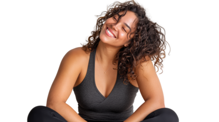 Smiling young woman with curly hair, wearing black athletic wear, sitting comfortably in a relaxed pose.