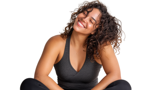 Smiling young woman with curly hair, wearing black athletic wear, sitting comfortably in a relaxed pose.