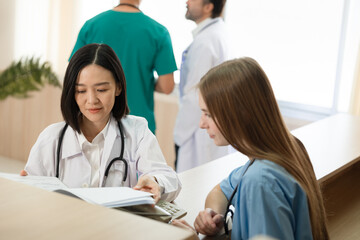 Asia doctor woman working and talking with Caucasian woman medical student at hospital	